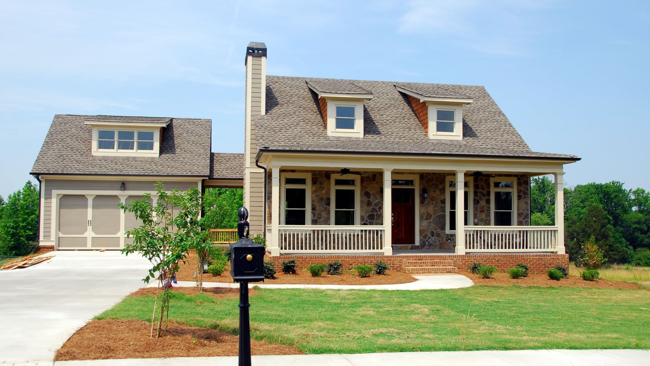 A two-story house with a front porch, a green lawn and a mailbox