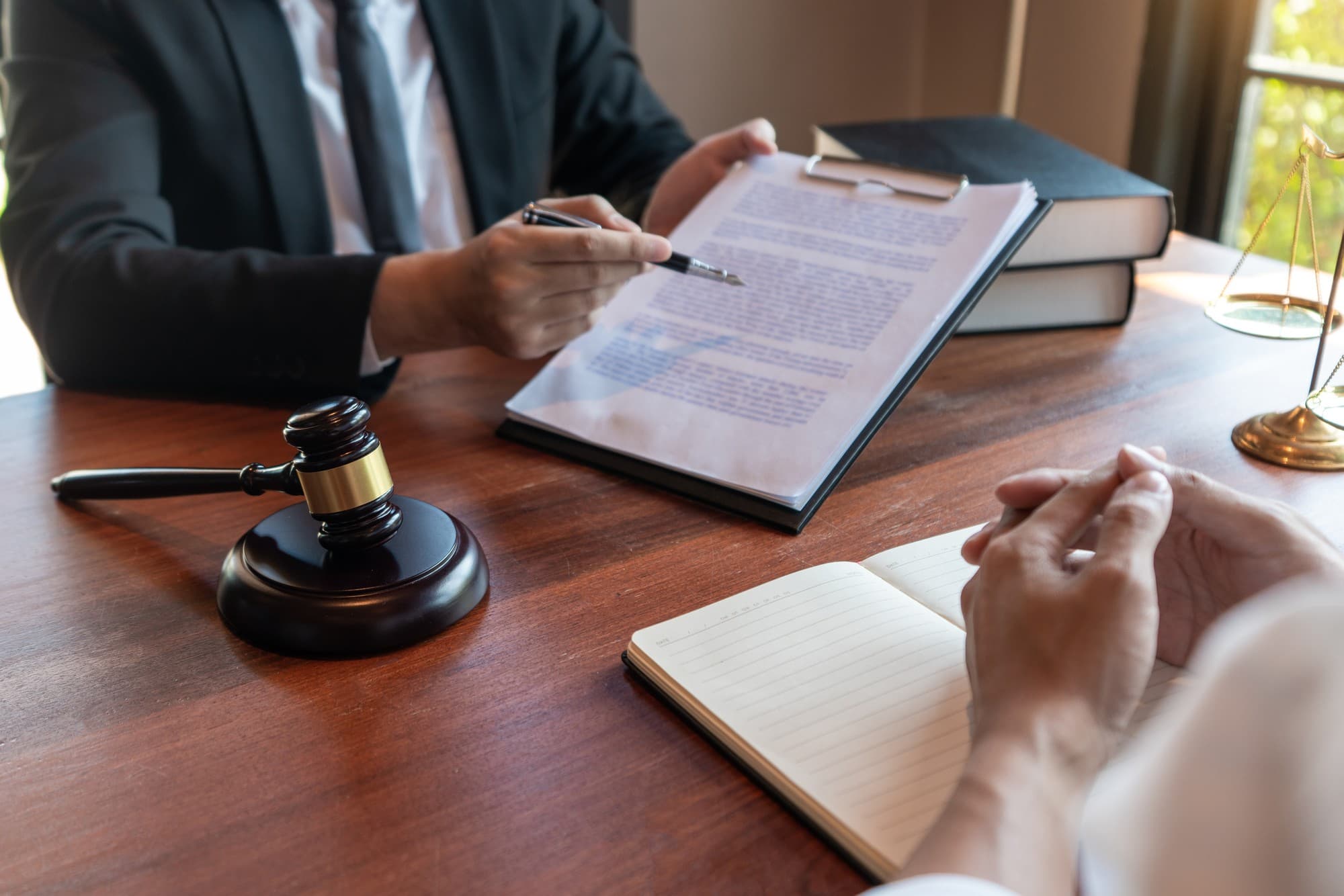 A lawyer going over a document with a client at a desk with a gavel and law books