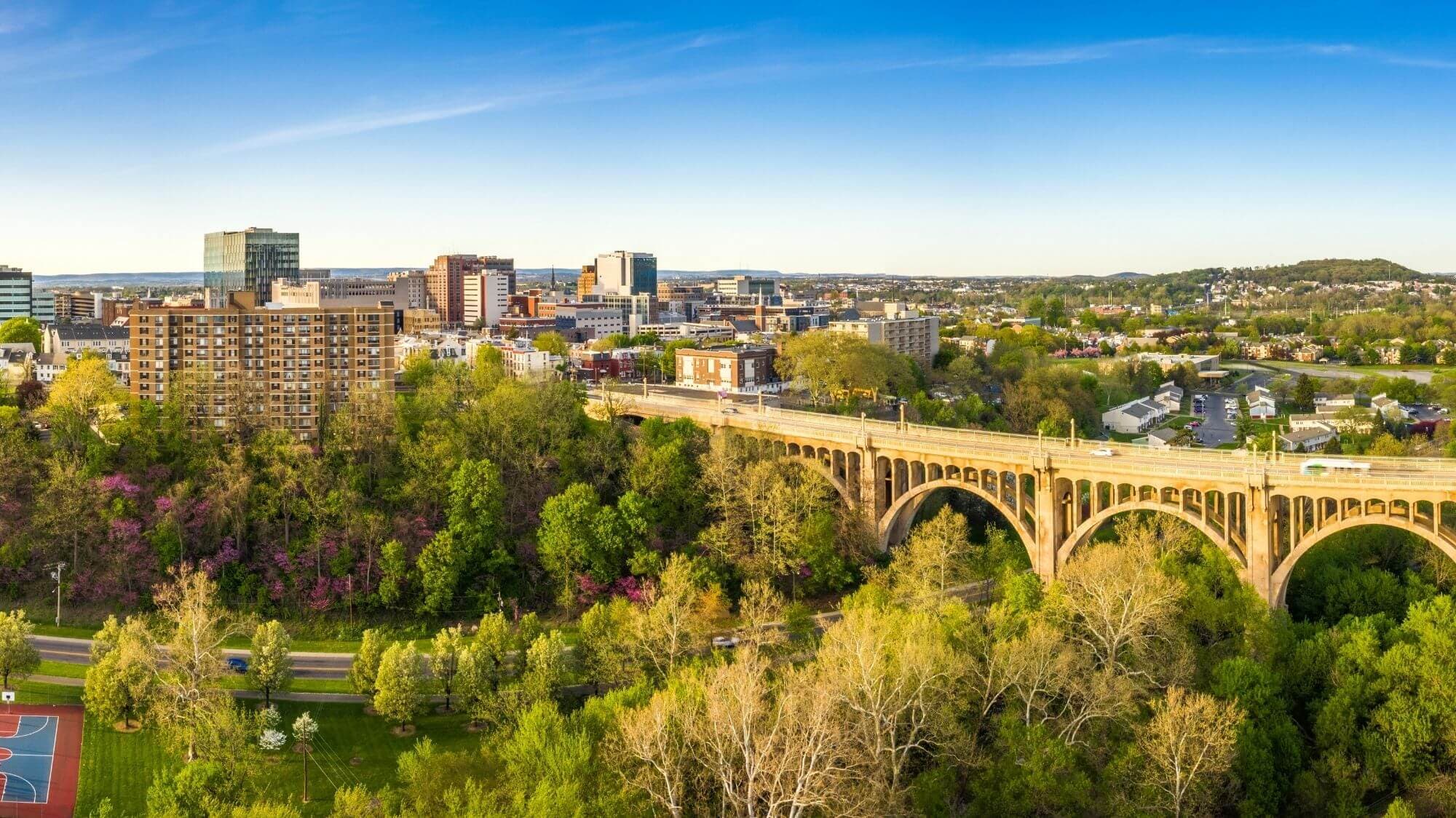 Downtown Allentown, Pennsylvania, with a concrete arch bridge crossing a wooded park valley in the foreground