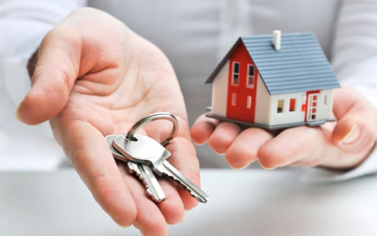 Hands holding out a set of house keys and a small model house